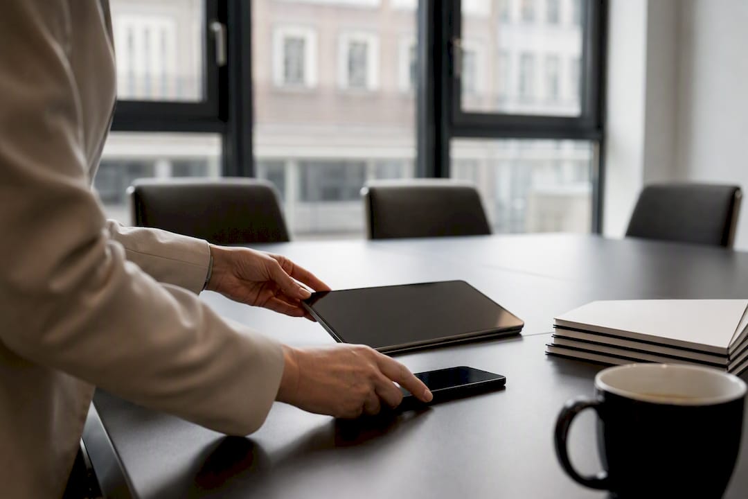 Hände, die ein dunkles, ausgeschaltetes Tablet und Smartphone bedienen